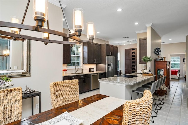 kitchen with light tile patterned floors, stainless steel appliances, crown molding, dark brown cabinetry, and recessed lighting