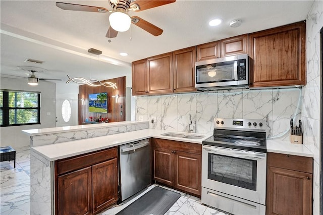 kitchen with sink, decorative light fixtures, appliances with stainless steel finishes, kitchen peninsula, and decorative backsplash