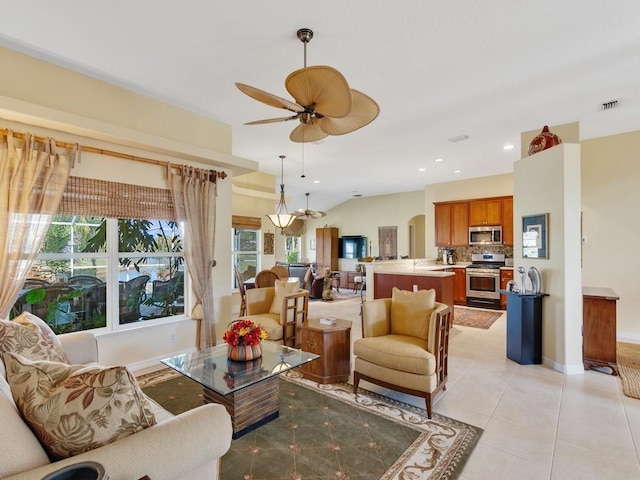 tiled living room featuring lofted ceiling and ceiling fan with notable chandelier