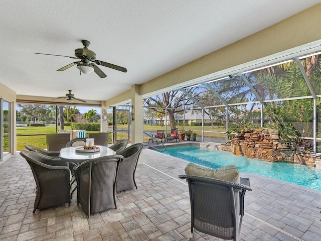 view of swimming pool featuring pool water feature, ceiling fan, a patio, and glass enclosure