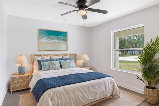 bedroom with hardwood / wood-style flooring, ceiling fan, and multiple windows