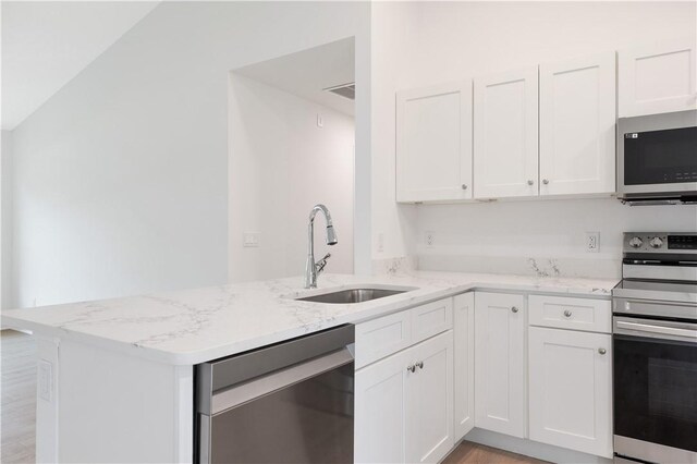 kitchen featuring white cabinets, kitchen peninsula, sink, and appliances with stainless steel finishes