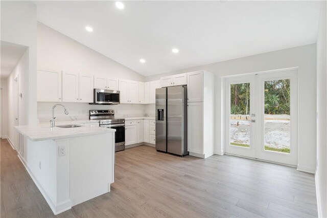 kitchen featuring kitchen peninsula, appliances with stainless steel finishes, light stone counters, sink, and white cabinets