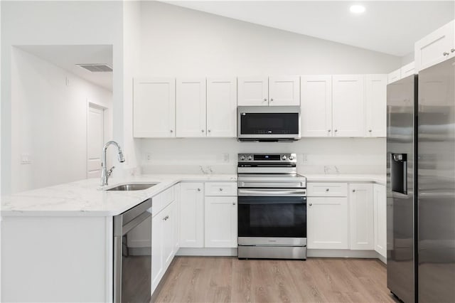 kitchen featuring white cabinets, appliances with stainless steel finishes, lofted ceiling, and sink