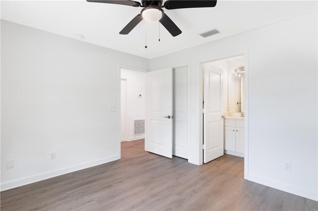 unfurnished bedroom with ceiling fan, light wood-type flooring, and ensuite bath