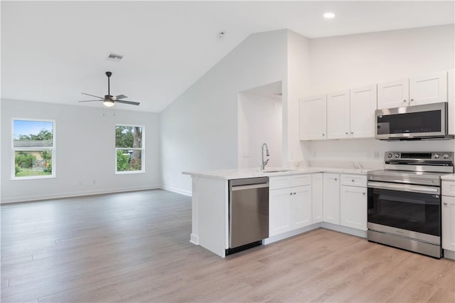 kitchen featuring sink, light wood-type flooring, appliances with stainless steel finishes, white cabinetry, and kitchen peninsula