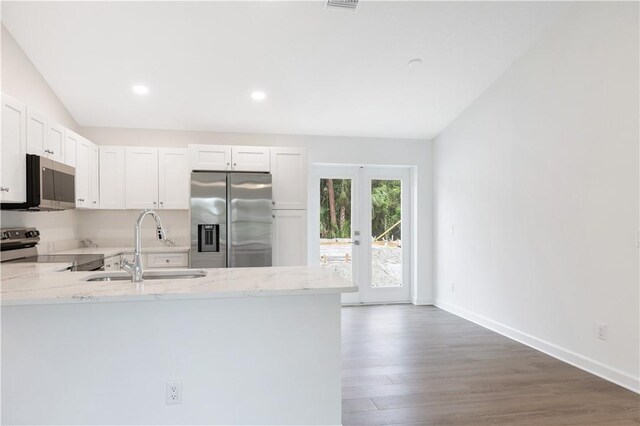 kitchen with white cabinetry, light stone countertops, appliances with stainless steel finishes, and vaulted ceiling