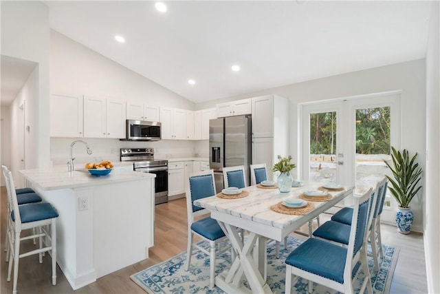 kitchen featuring white cabinets, light wood-type flooring, a kitchen bar, kitchen peninsula, and stainless steel appliances