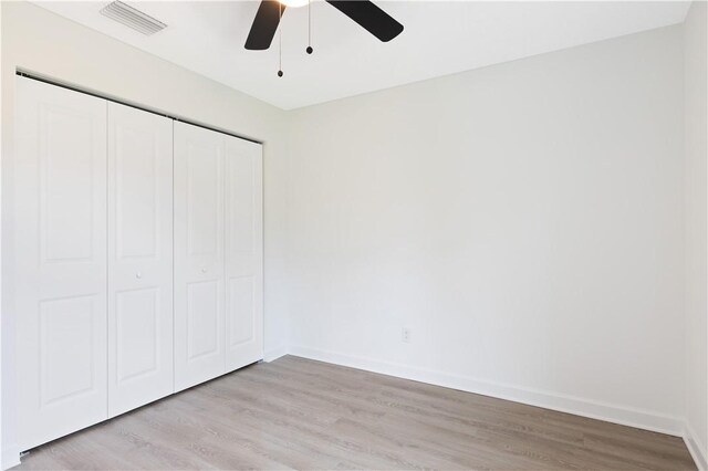 unfurnished bedroom with ceiling fan, a closet, and light wood-type flooring