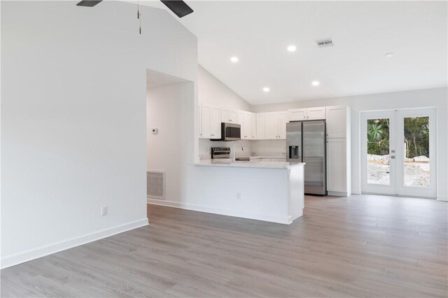 kitchen featuring high vaulted ceiling, white cabinets, ceiling fan, light hardwood / wood-style floors, and stainless steel appliances