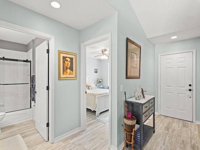 hall with light wood-type flooring, baseboards, recessed lighting, and a barn door