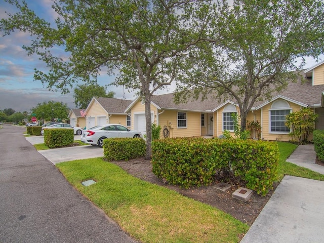 ranch-style home featuring concrete driveway, an attached garage, and a front yard