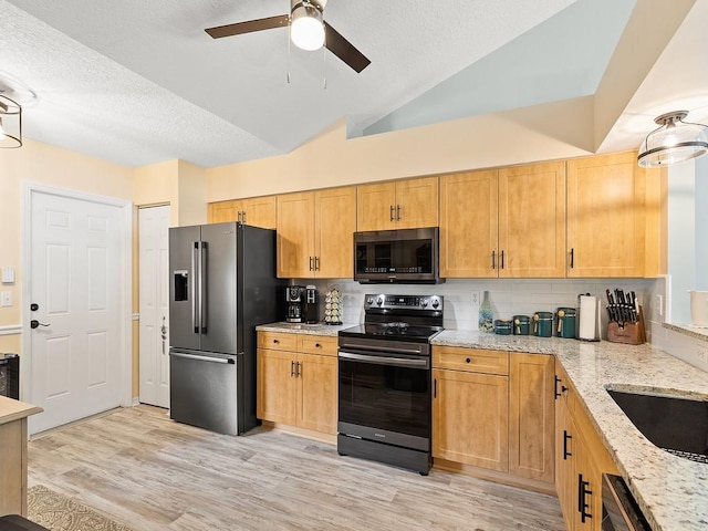 kitchen with stainless steel appliances, ceiling fan, backsplash, light stone counters, and a textured ceiling