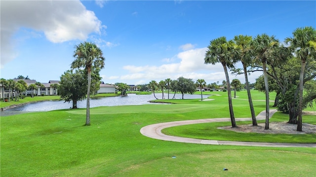 view of property's community with a lawn, view of golf course, and a water view