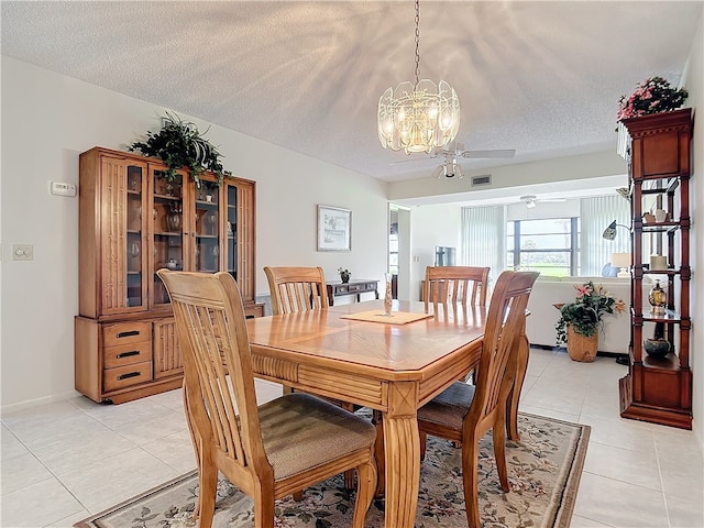 tiled dining space with ceiling fan with notable chandelier and a textured ceiling