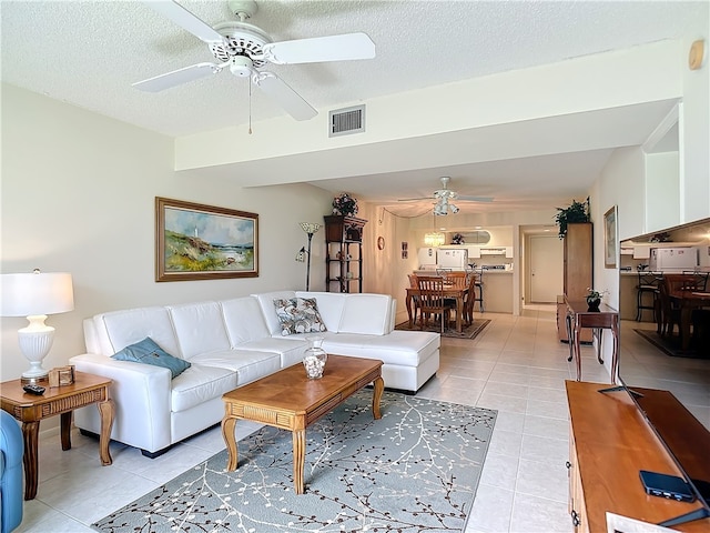 living room featuring a textured ceiling, ceiling fan, and light tile patterned flooring