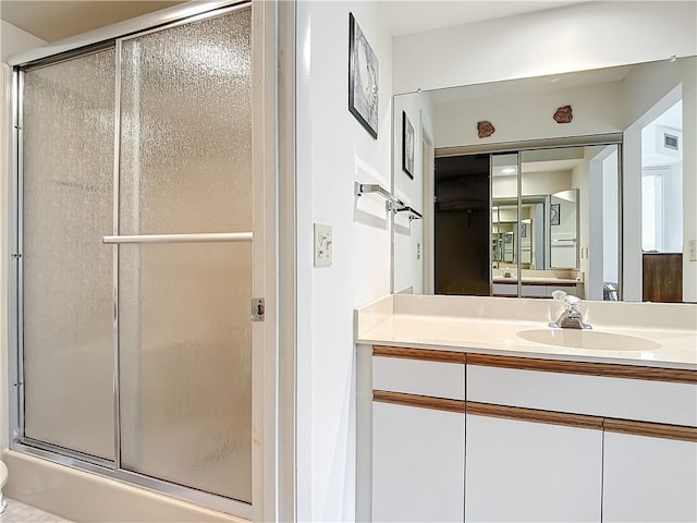 bathroom with a shower with door and vanity