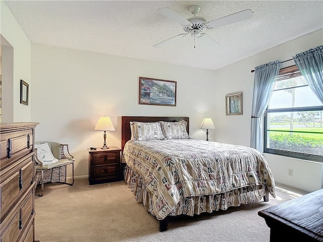 bedroom with ceiling fan, a textured ceiling, and light colored carpet