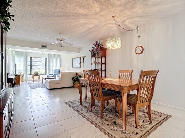 dining area with light tile patterned floors, ceiling fan with notable chandelier, a textured ceiling, and visible vents