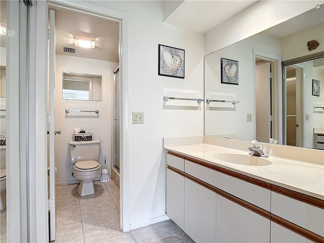 bathroom featuring vanity, tile patterned floors, toilet, and an enclosed shower