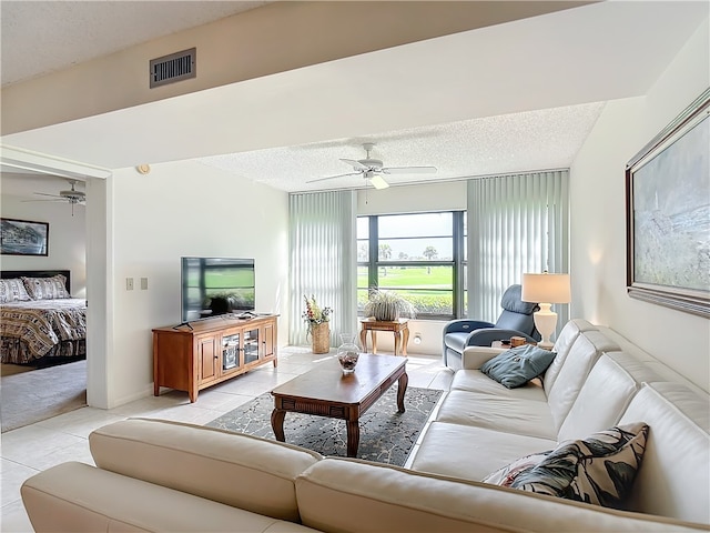 living room with ceiling fan, a textured ceiling, and light tile patterned floors