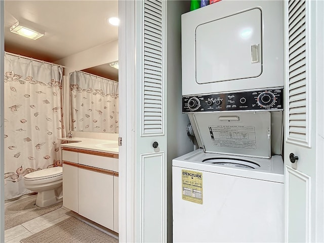 clothes washing area with light tile patterned floors and stacked washer and dryer