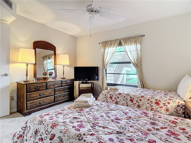 bedroom featuring a textured ceiling, light carpet, and ceiling fan