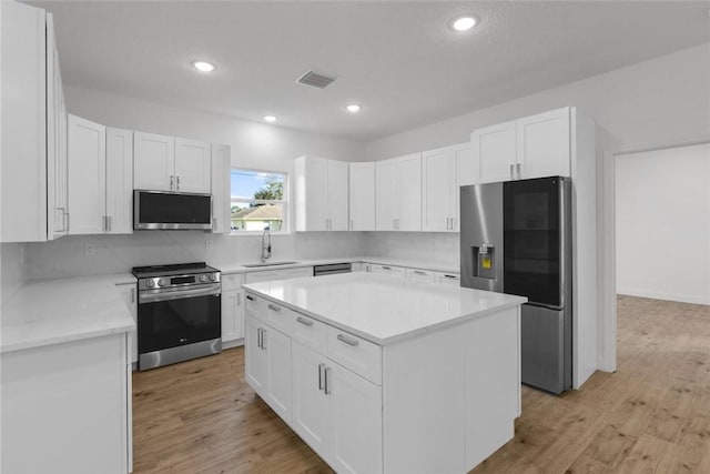 kitchen featuring a kitchen island, tasteful backsplash, white cabinetry, sink, and stainless steel appliances