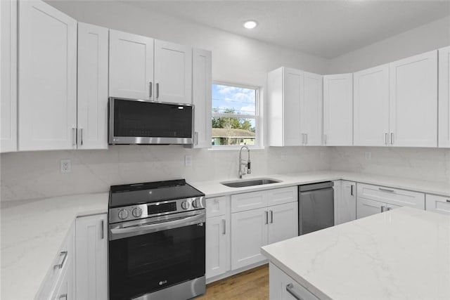 kitchen featuring light stone countertops, white cabinetry, appliances with stainless steel finishes, and sink