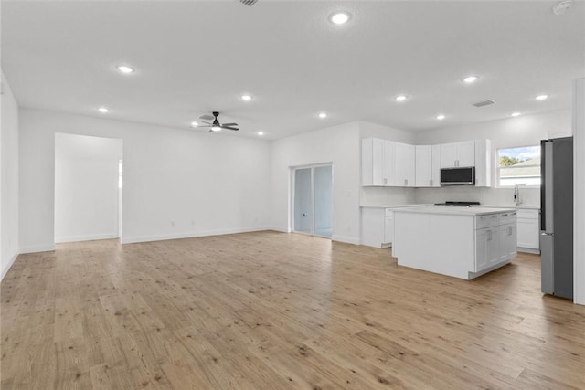 kitchen with ceiling fan, a center island, white cabinets, and light wood-type flooring