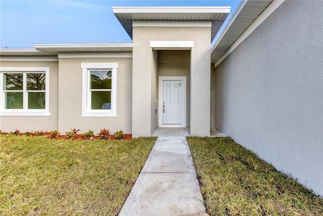 view of exterior entry with a lawn