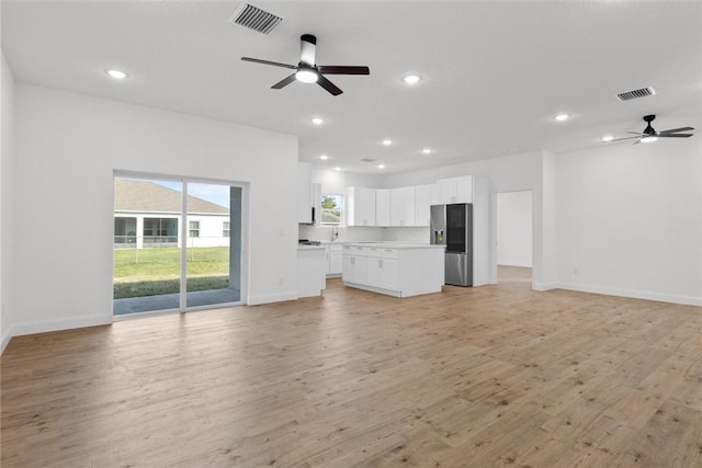 unfurnished living room featuring ceiling fan and light wood-type flooring