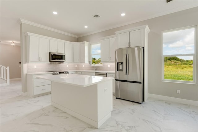 kitchen featuring stainless steel appliances, a kitchen island, light countertops, and white cabinets