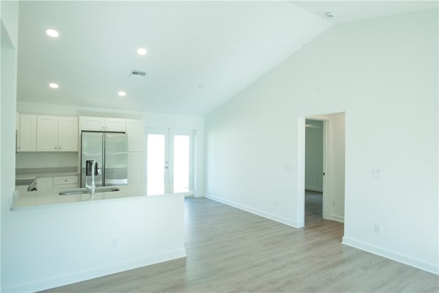 interior space with high vaulted ceiling, sink, french doors, and light hardwood / wood-style flooring