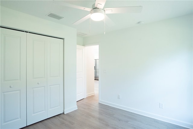 unfurnished bedroom with stainless steel fridge, light hardwood / wood-style floors, ceiling fan, and a closet