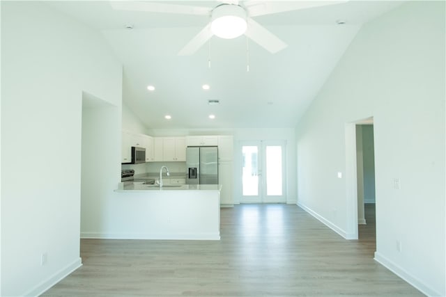 kitchen with white cabinets, kitchen peninsula, appliances with stainless steel finishes, and light hardwood / wood-style floors