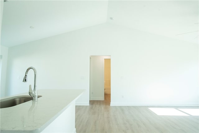 living room featuring sink, light wood-type flooring, and high vaulted ceiling