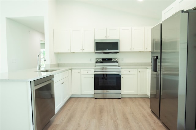 kitchen featuring stainless steel appliances, white cabinets, sink, and vaulted ceiling