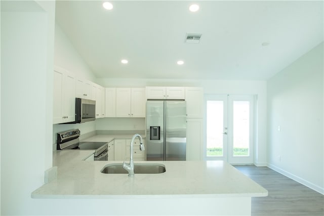 kitchen featuring stainless steel appliances, white cabinetry, sink, kitchen peninsula, and lofted ceiling