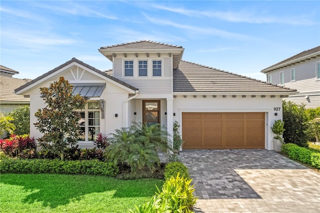 view of front of home featuring decorative driveway, stucco siding, a garage, a tiled roof, and a front lawn