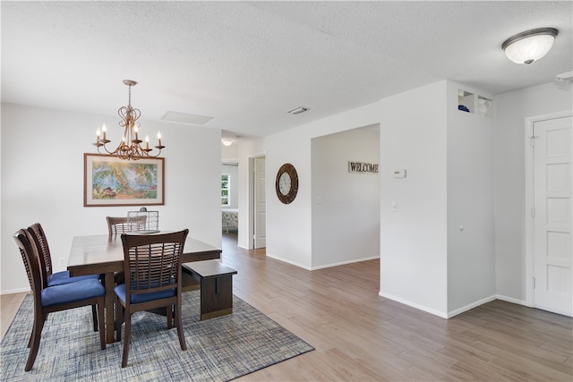 dining area featuring wood-type flooring, a textured ceiling, and an inviting chandelier