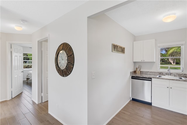 kitchen with dishwasher, plenty of natural light, sink, and white cabinets