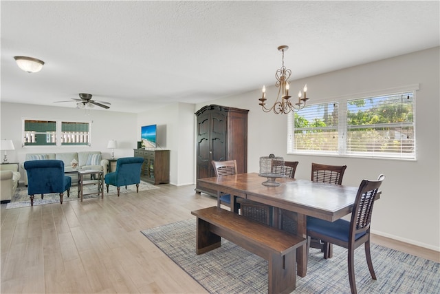 dining room with a textured ceiling, ceiling fan with notable chandelier, and light hardwood / wood-style flooring