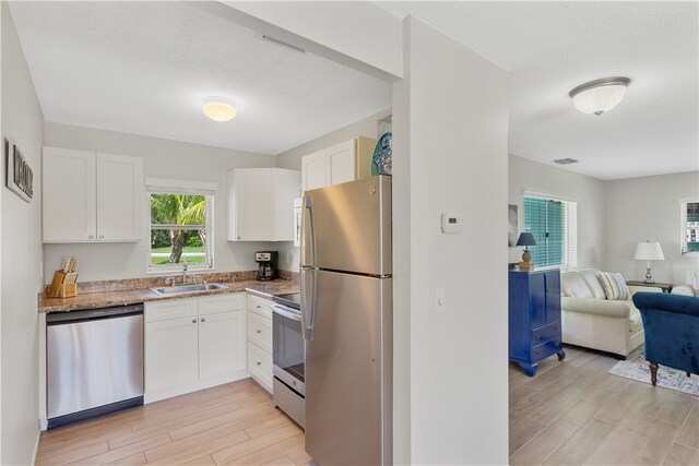 kitchen with white cabinetry, appliances with stainless steel finishes, and light wood-type flooring