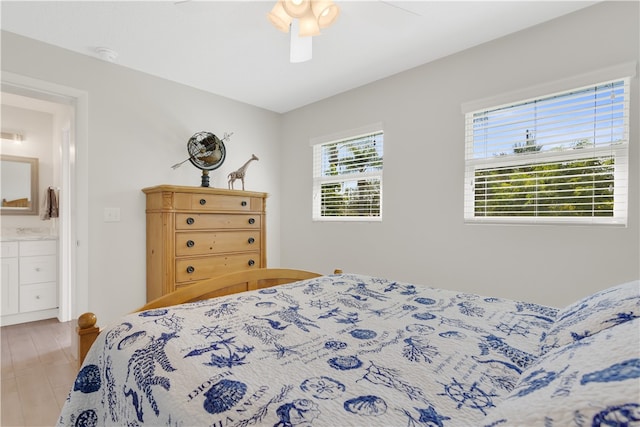 bedroom with ensuite bathroom, hardwood / wood-style flooring, and ceiling fan