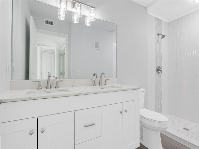 bathroom with wood-type flooring, toilet, tiled shower, and vanity