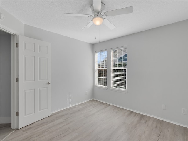 spare room with light wood-type flooring, ceiling fan, and a textured ceiling