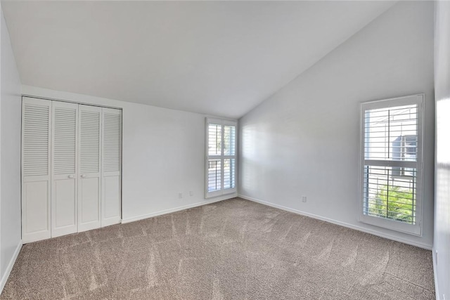 unfurnished bedroom featuring multiple windows, lofted ceiling, and carpet