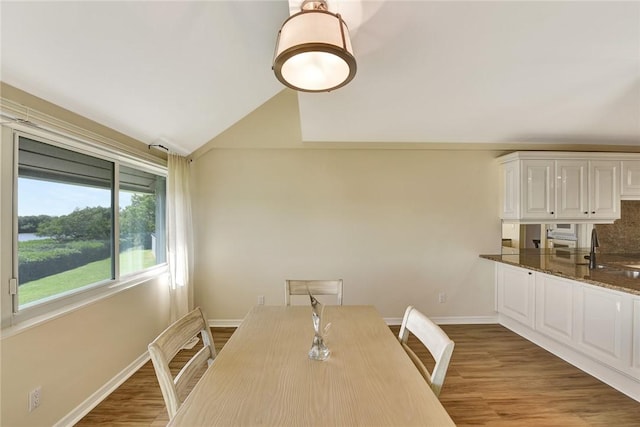 dining area with vaulted ceiling, sink, and wood-type flooring