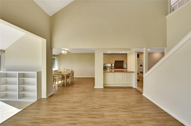 living room with high vaulted ceiling and light hardwood / wood-style floors